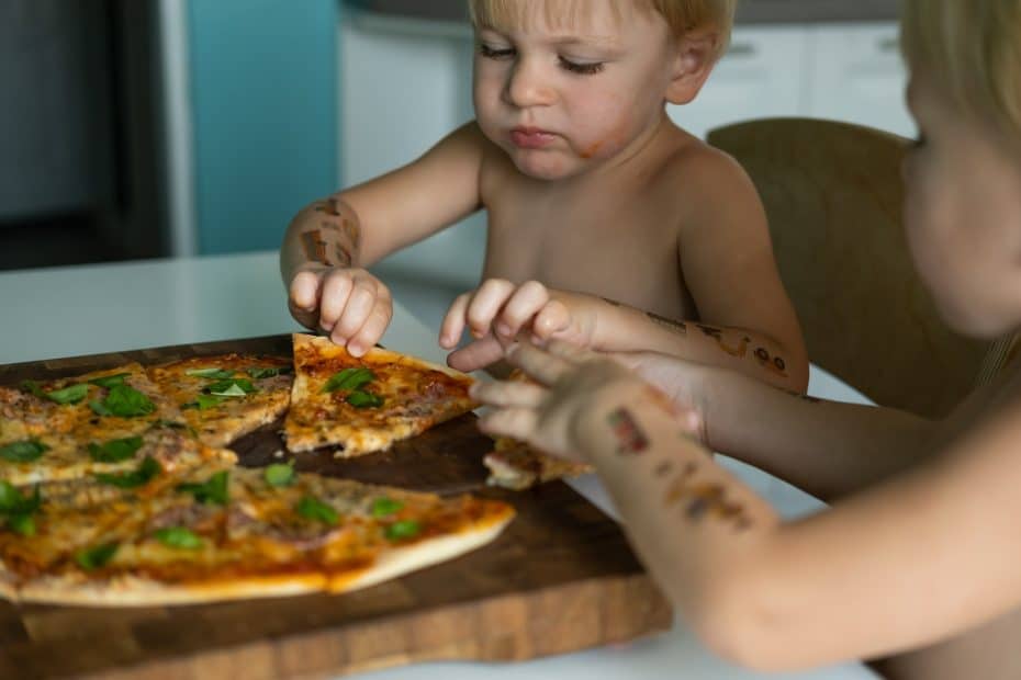 To gutter spiser hjemmelaget pizza med forskjellige råvarer